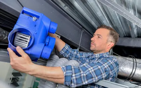 Un technicien installe un nouveau bloc VMC. L'entretien vmc obligatoire garantit un air sain dans votre logement.