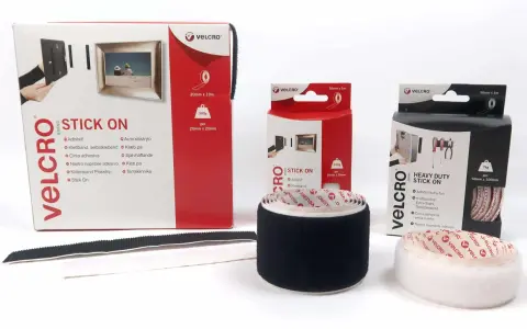 Comment poser du velcro adhésif : démonstration avec des rouleaux et boîtes de différentes tailles pour fixer cadres et outils.