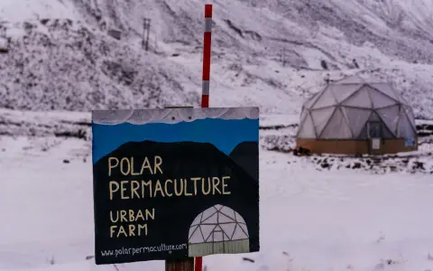 Panneau "Polar Permaculture Urban Farm" devant un dôme géodésique enneigé, rappelant la réserve mondiale de semences du Svalbard.