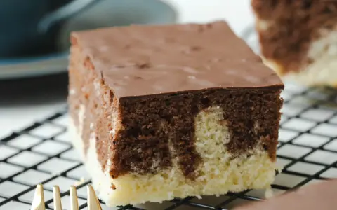 Ein Stück saftiger Marmorkuchen vom Blech, mit Schokoladenglasur, auf einem Kuchengitter.