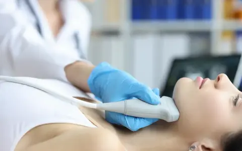 Fizjoterapeuta wykonuje badanie USG szyi, co może być częścią terapii stawu skroniowo-żuchwowego.