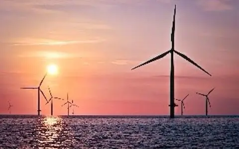 Windräder im Meer bei Sonnenuntergang. Ein Symbol für die EEG Umlage Befreiung und eine saubere Zukunft.