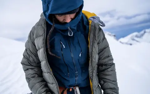 Person in Daunenjacke in winterlicher Berglandschaft. Die Daunenjacke waschen ist wichtig für die Langlebigkeit.