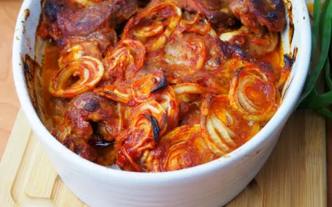 Karkówka pieczona w plastrach z cebulą i ketchupem, zapiekana w naczyniu.