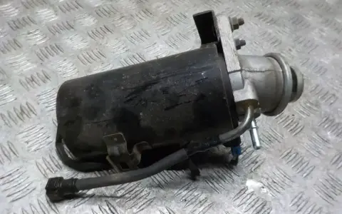 Filtr paliwa z widocznymi przewodami i mocowaniem na metalowym tle.
