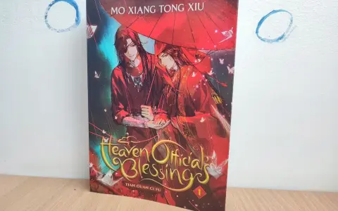 Okładka książki "Heaven Official's Blessing" z dwoma mężczyznami pod czerwonym parasolem.