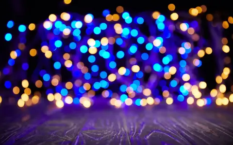 Luci blu e dorate creano un magico effetto bokeh su uno sfondo scuro, con un piano in legno in primo piano.