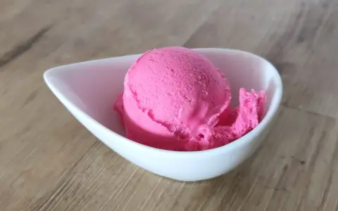 Ein Löffel leuchtend pinkes Eis in einer weißen Schale. Vielleicht ist das die Antwort auf die Frage, warum es kein Kirscheis gibt – weil dieses hier so gut ist!
