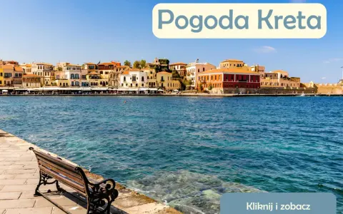 Słoneczna pogoda na Krecie w lipcu. Widok na port z kolorowymi kamienicami i ławką nad turkusową wodą.