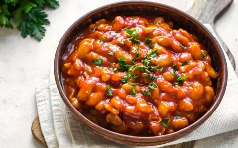 Fagioli in salsa rossa, guarniti con prezzemolo fresco. Un piatto saporito che si possono cuocere all'uccelletto.