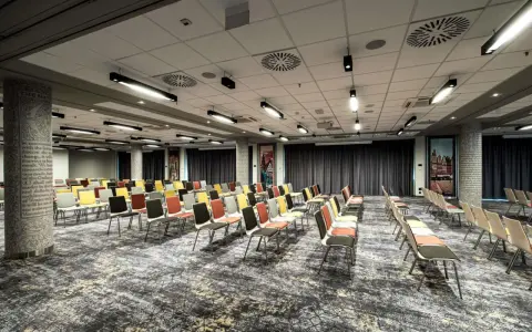 Sala konferencyjna w hotelu Mercure Wrocław, przygotowana na wydarzenie. Rzędy kolorowych krzeseł czekają na gości.