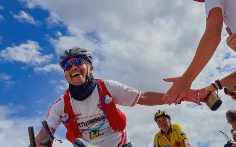 Glücklicher Radfahrer gibt High-Five während Paris Brest Paris. Ein weiterer Radfahrer im Hintergrund.