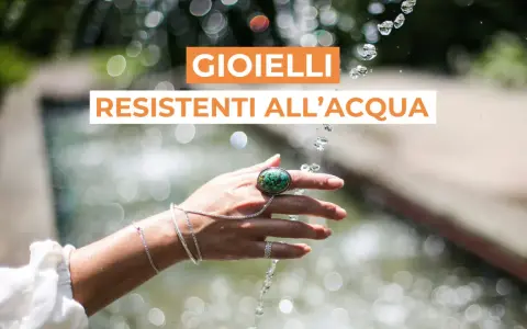 Mano adornata con gioielli che non si rovinano con l'acqua, sotto un getto d'acqua scintillante.
