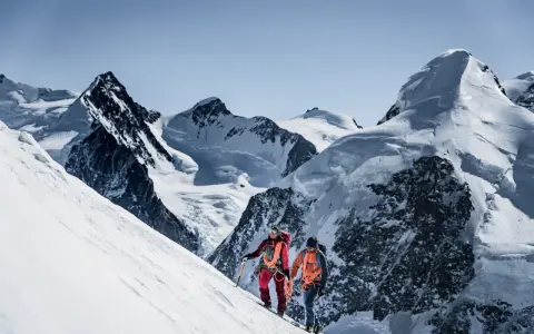 Zwei Bergsteiger, ein beal escaper-Team, steigen einen schneebedeckten Hang hinauf, umgeben von majestätischen, eisigen Gipfeln.