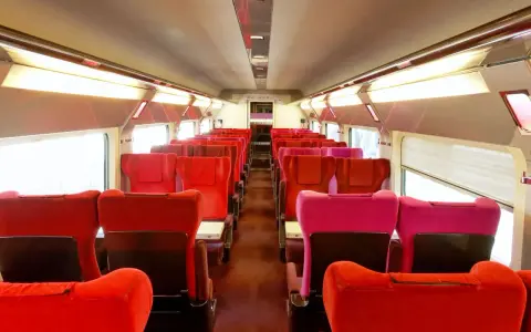Rows of red and pink seats inside a train car, ready for passengers on the best train from Amsterdam to Paris.