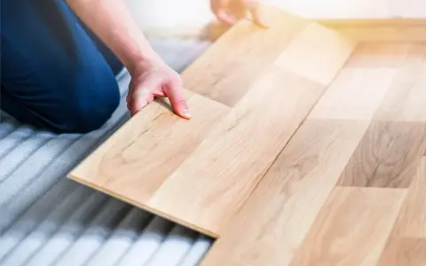 Man colocando una tabla de madera para poner suelo de tarima flotante.