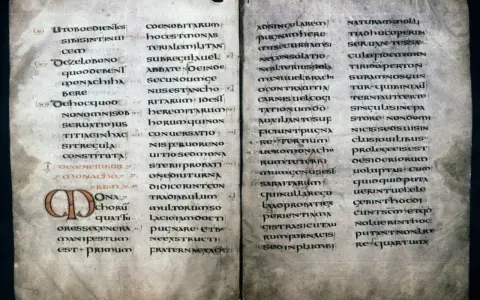 Ancient manuscript page with Latin text, likely a summary of St. Benedict's Rules, featuring ornate initial letters.