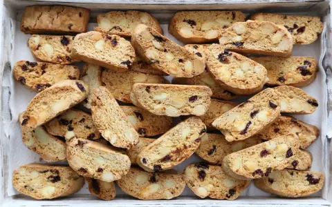Un vassoio pieno di croccanti biscotti toscani, ricchi di mandorle e mirtilli rossi, pronti per essere inzuppati.