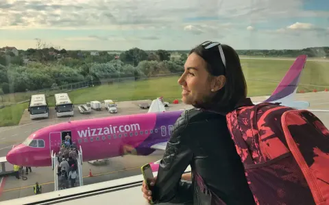 Kobieta z plecakiem czeka na lot Wizzair. W samolocie można zabrać podręczny bagaż, np. plecak i telefon.
