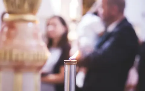 Płonąca świeca podczas uroczystości. Zastanawiasz się, kogo zaprosić na chrzciny?