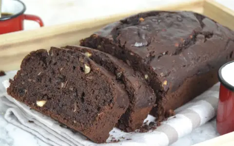 Bizcocho de platano y chocolate, recién horneado y cortado en rebanadas, con trozos de nuez visibles.