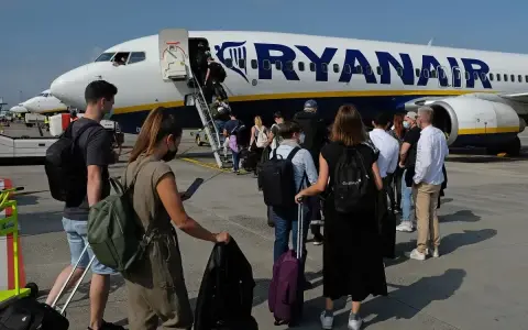 Pasażerowie wchodzą po schodkach do samolotu Ryanair.