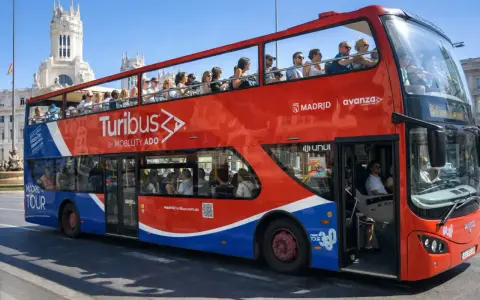 Tourists enjoy a hop on hop off bus tour of Madrid, Spain, with the iconic Turibus double-decker bus.