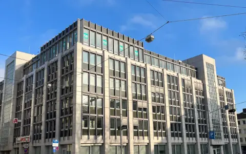 Modernes Bürogebäude in Kassel mit vielen Fenstern und "FOM"-Logos. Eine Apotheke ist im Erdgeschoss sichtbar.