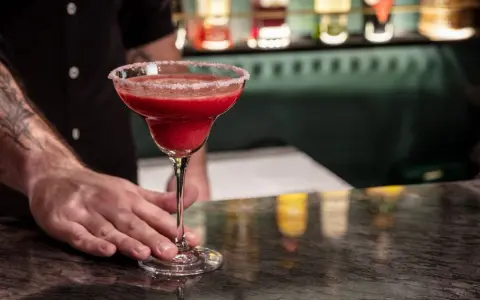 Margarita przepis: orzeźwiający, czerwony drink z solą na brzegu kieliszka, podawany przez barmana.