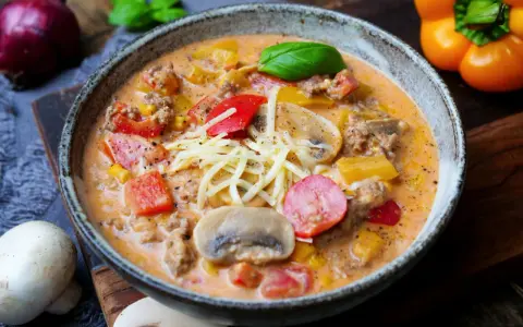 Herzhaftes pizzasuppe rezept mit Hackfleisch, Paprika, Mais und Pilzen, garniert mit Käse und Basilikum.
