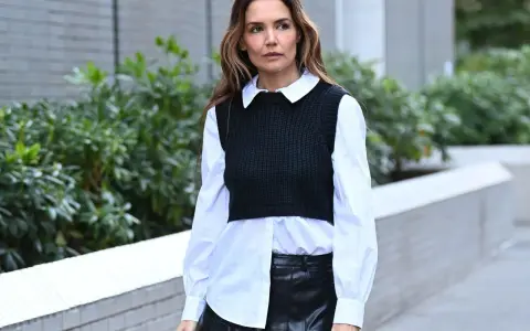Donna con camicia bianca e gilet nero, la camicia dentro i pantaloni di pelle nera.