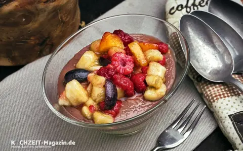 Schokoladige smoothie bowl mit frischen Himbeeren, Bananenstücken und Blaubeeren. Ein gesunder Genuss!