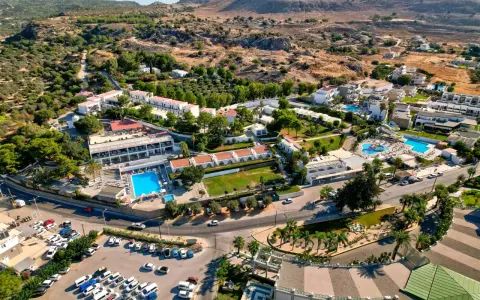 Widok z lotu ptaka na hotel Ellia Rodos z basenami, zjeżdżalniami i parkingiem pełnym samochodów.