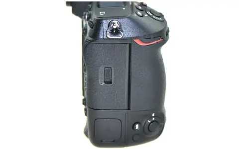 Boczny widok aparatu Nikon Z9, gotowego do testów. Widoczny slot na kartę pamięci i przyciski sterujące.
