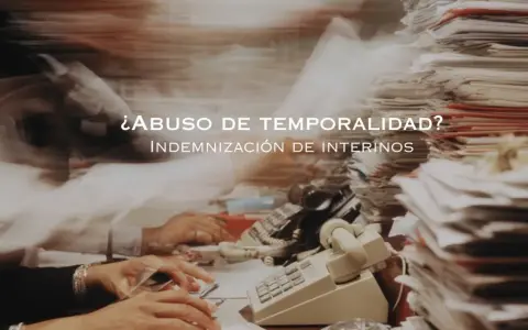 ¿Abuso de temporalidad? Indemnización de interinos tras 3 años. Escritorio caótico con papeles y teléfonos.