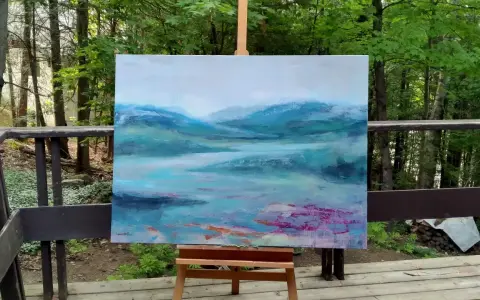 Un paysage abstrait aux teintes bleues et vertes, évoquant des montagnes brumeuses et un lac. Le fond de tableau peinture est posé sur un chevalet, en extérieur, entouré de verdure.