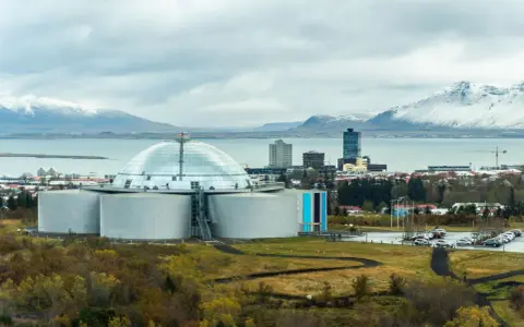 Große Kuppel und Tanks, Teil der island stromerzeugung, mit schneebedeckten Bergen im Hintergrund.