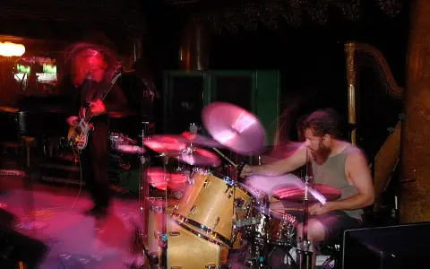 Ein Bassist und ein Schlagzeuger einer Stoner Rock Band in Aktion. Die Lichter und Bewegungen erzeugen eine dynamische Atmosphäre.