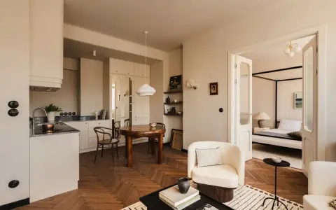 Jak urządzić salon? Jasne, przytulne wnętrze z aneksem kuchennym, jadalnią i sypialnią. Drewniana podłoga w jodełkę, wygodne fotele i stylowe dodatki.