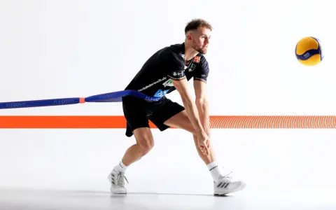 Volleyballspieler im Krafttraining mit Widerstandsband, bereit für den Aufschlag.
