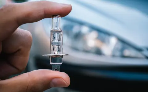 Un dedo sostiene una bombilla de coche, lista para iluminar el camino con sus luces largas.