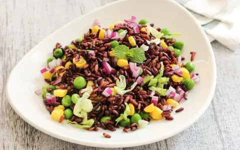 Insalata colorata con riso venere, piselli, mais, cipolla rossa e lattuga. Un'idea fresca per le tue riso venere ricette.