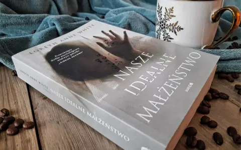 Książka "Nasze idealne małżeństwo" na drewnianym blacie, obok filiżanki i ziaren kawy.