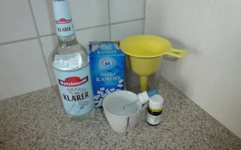Zutaten für Ouzo selber machen: Klarer Schnaps, Kandiszucker, ein Trichter und eine Pipette.