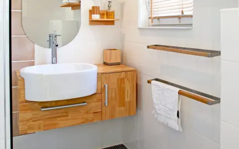 Meuble de salle de bain en bois clair, avec vasque blanche et robinetterie moderne. La hauteur du meuble est idéale pour un accès facile.
