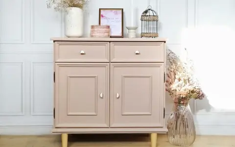 Meuble vintage repeint en rose poudré, prêt à peindre sur ancienne peinture bois. Décoré de fleurs séchées et d'une cage décorative.