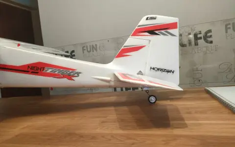Modellflugzeug mit Aufschrift "NIGHT TIMBER" und "Eflite" Logo. Das Flugzeug steht auf einem Holztisch, bereit zum Flug.