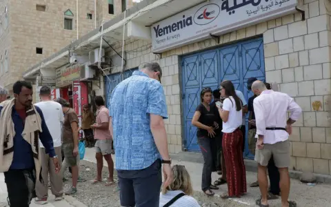 Ludzie stoją przed biurem Yemenia Airways. Czy Jemen jest bezpieczny? To pytanie zadają sobie podróżni, obserwując codzienne życie w tym kraju.