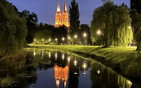 Wieczorny spacer nad rzeką we Włocławku. Podświetlona katedra odbija się w wodzie, tworząc magiczny widok. Idealne włocławek atrakcje na weekend.