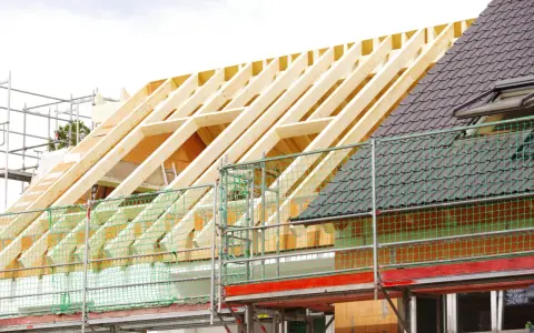 Neuer Dachstuhl im Bau, Gerüst und Schutznetze. Informieren Sie sich über die dachstuhl erneuern kosten.